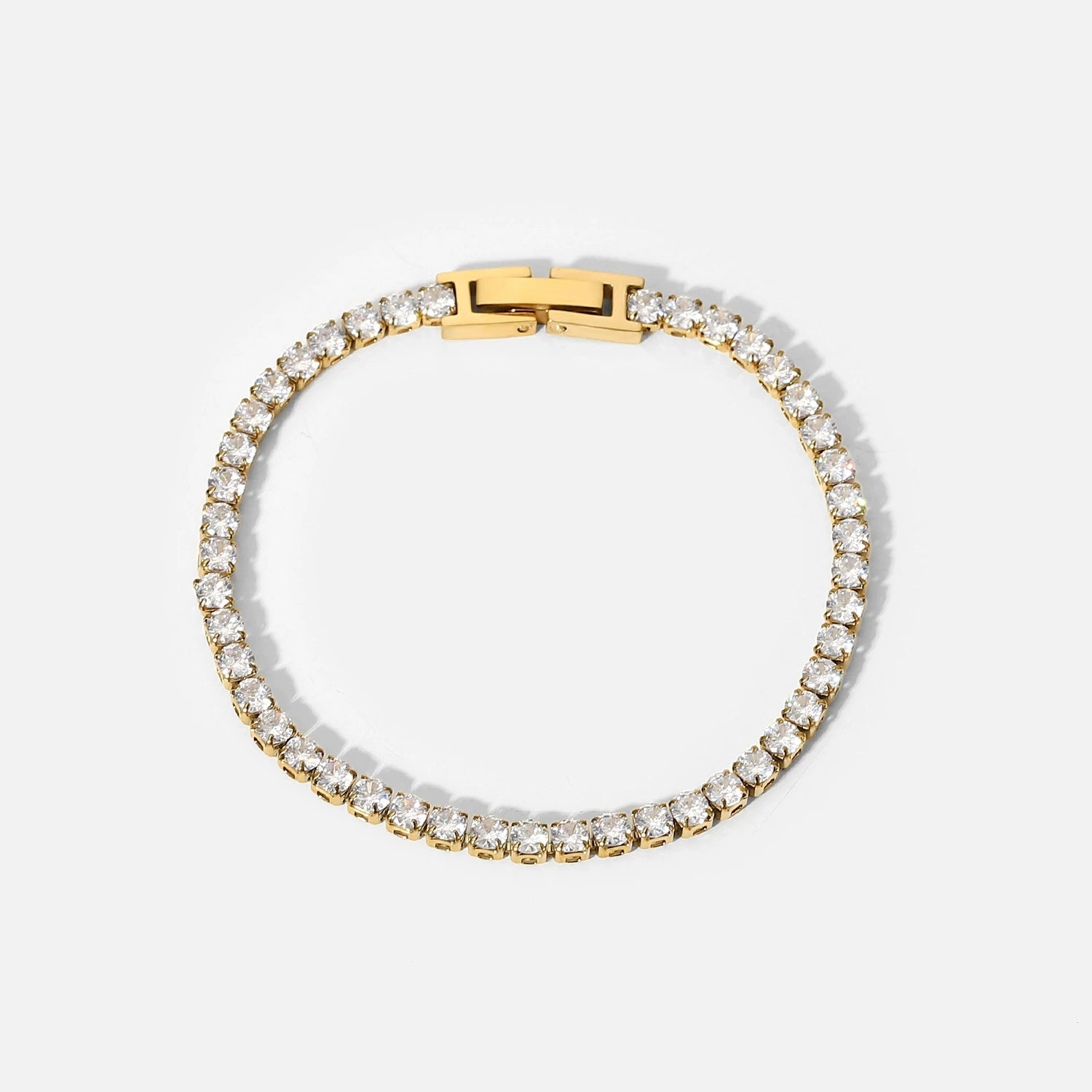 Gold bracelet with clear gemstones on a white background