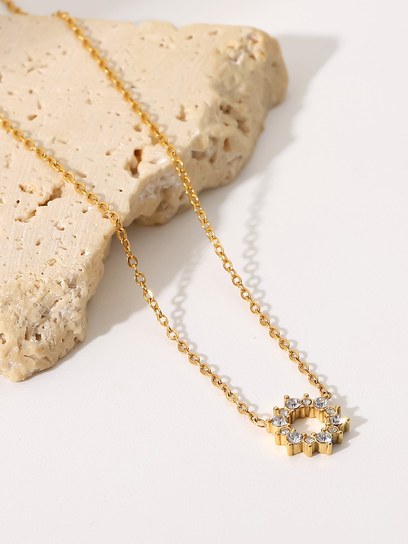 Gold necklace with a star-shaped pendant on a light background