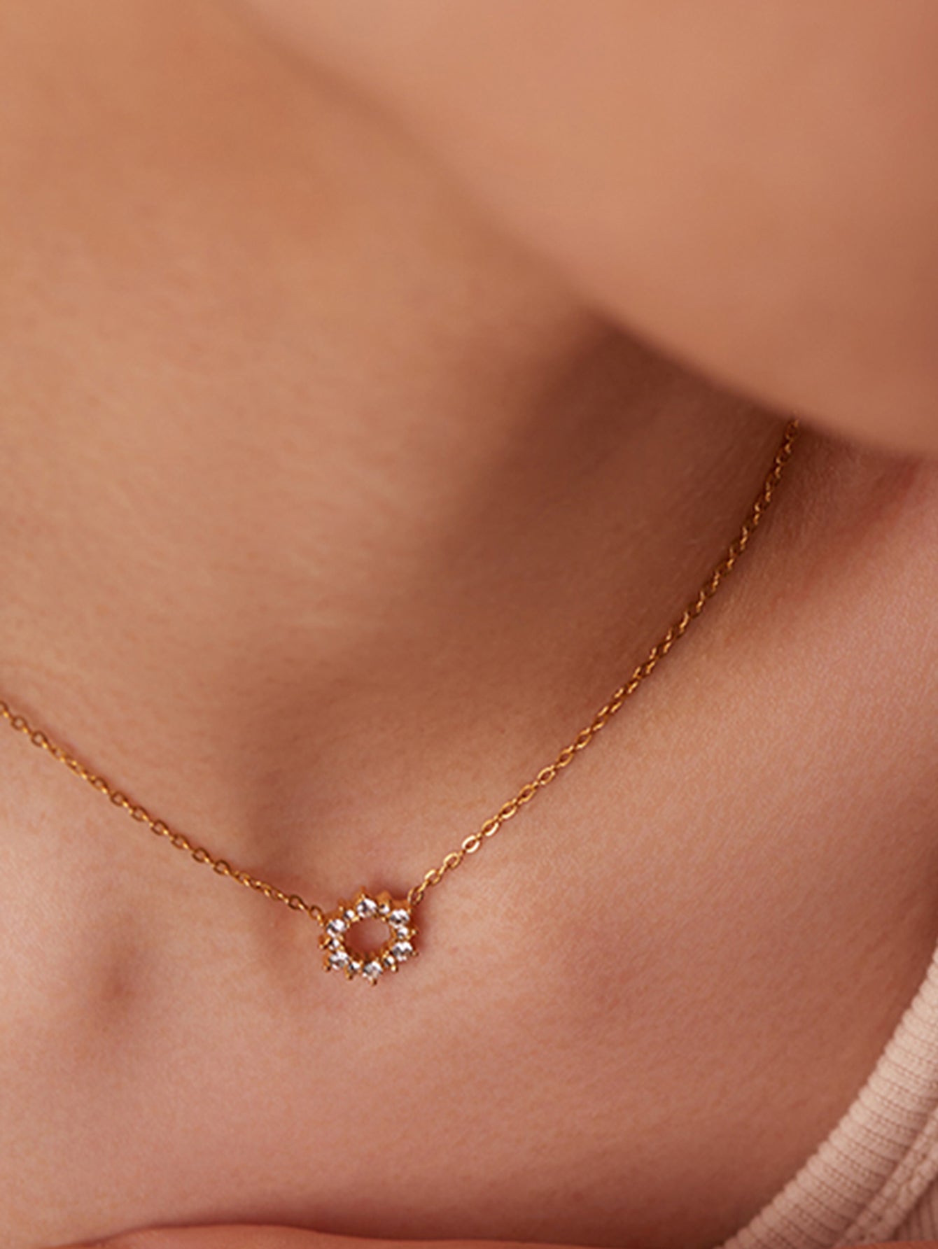 Rose gold necklace with a small diamond pendant on a person's neck