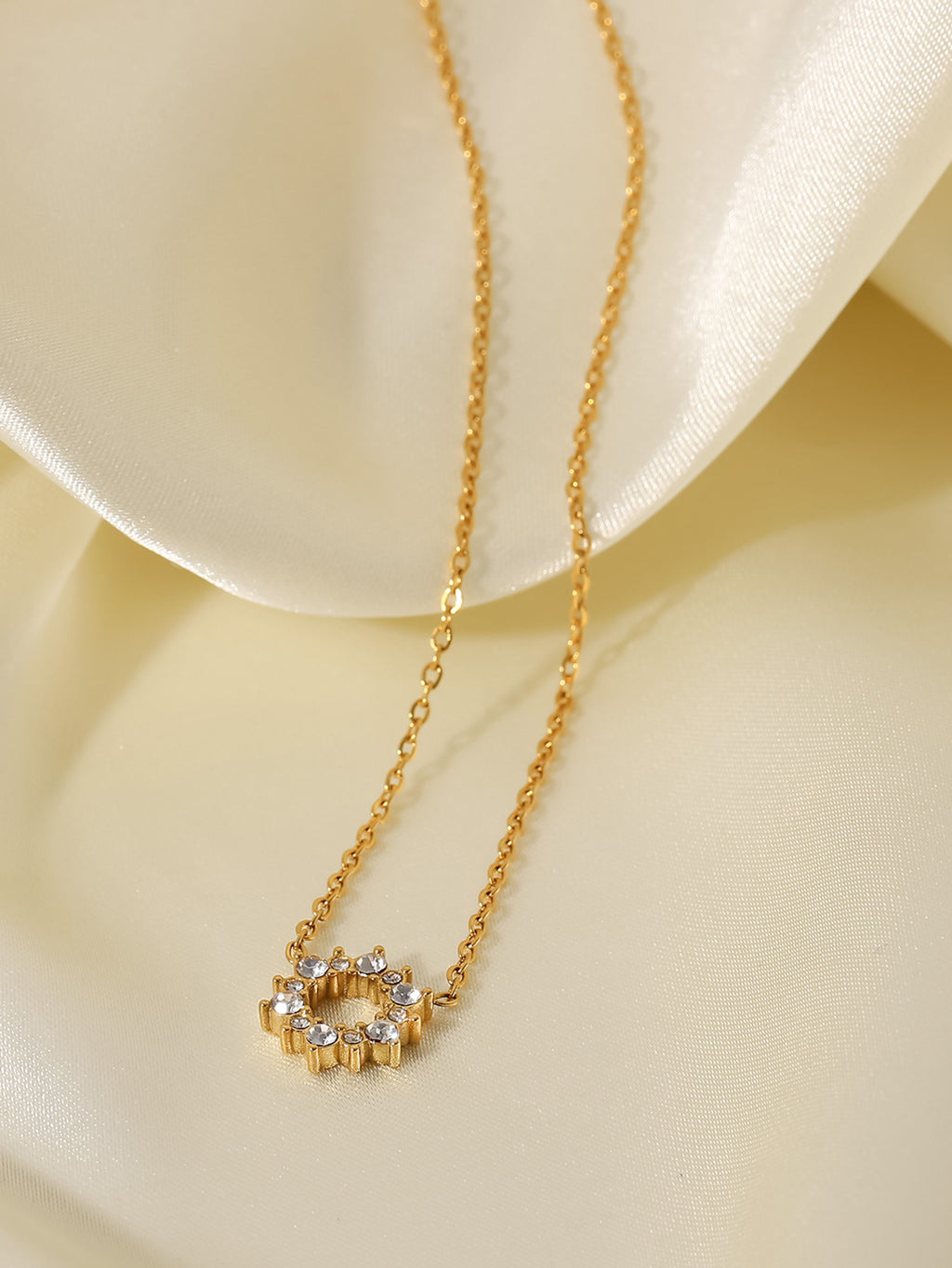 Gold necklace with a small pendant on a beige fabric background