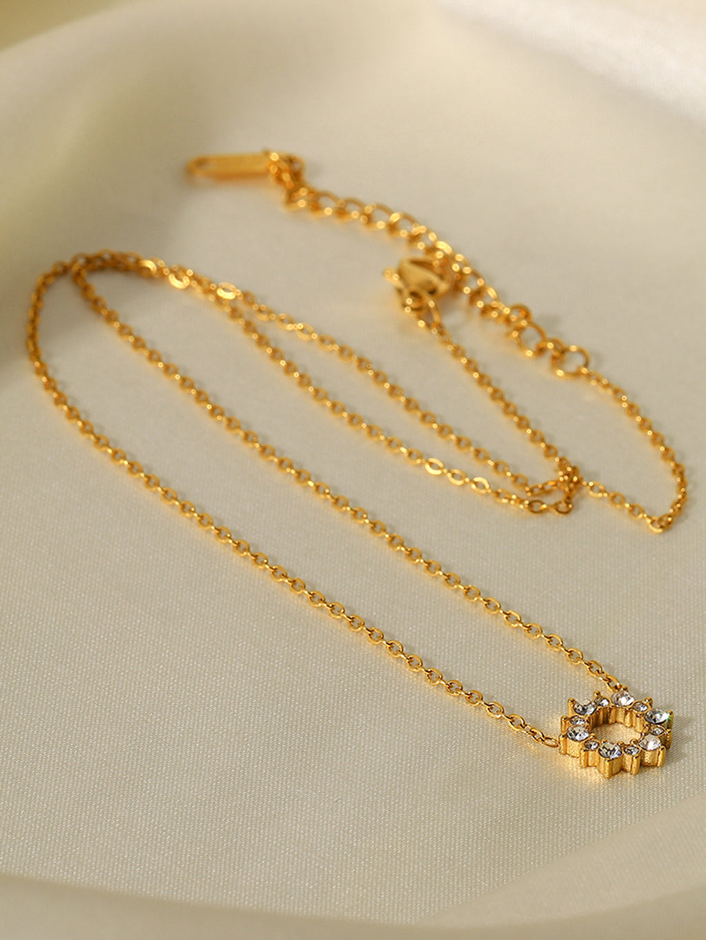 Gold necklace with a small decorative clasp on a beige background