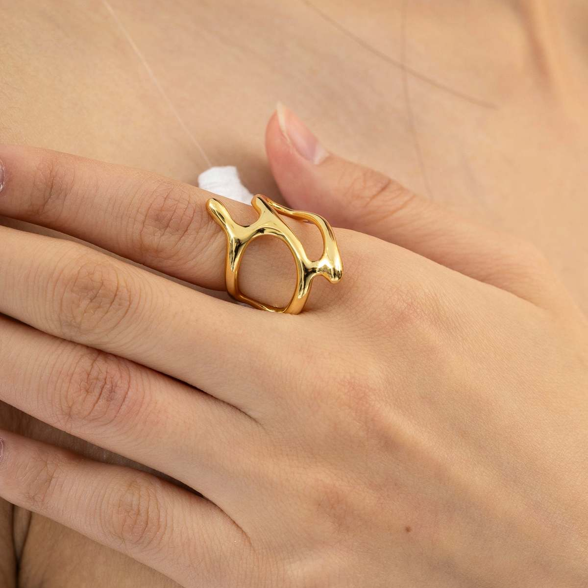 Gold ring on a hand against a neutral background