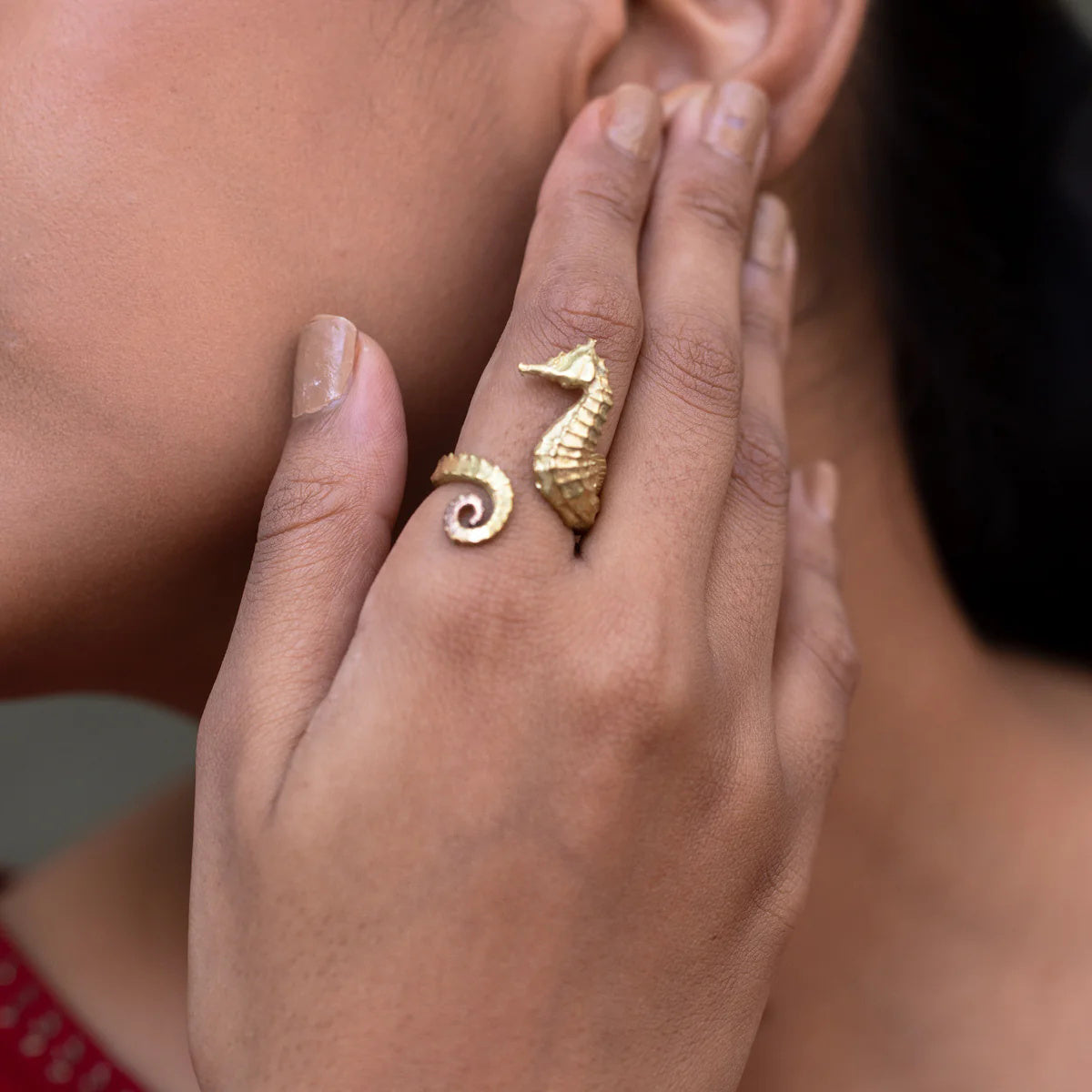 Close-up of a hand wearing two gold rings with intricate designs.