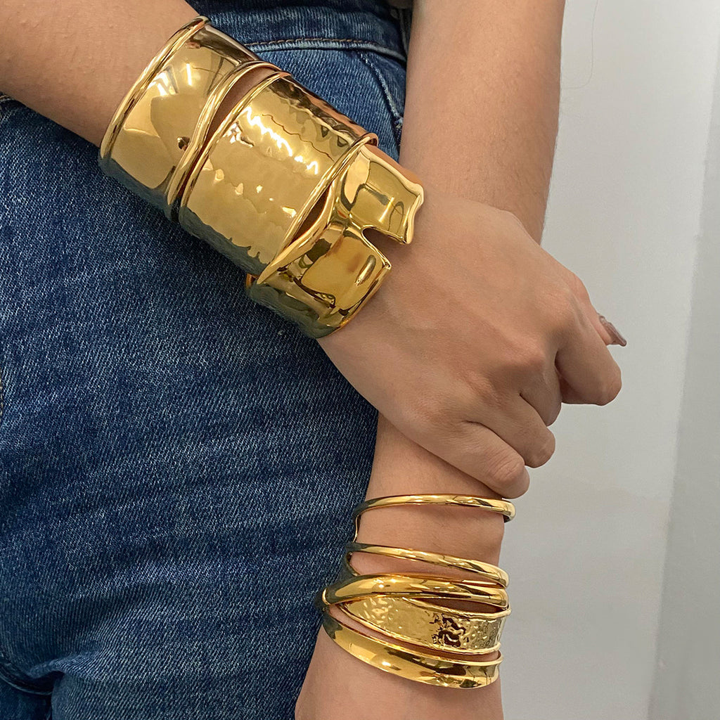 Gold bracelets on a person's wrist with a denim background
